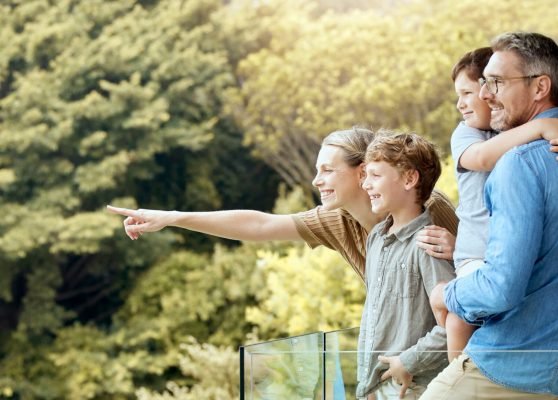 Happy, family and and pointing on balcony, parents and bonding with children, smile and love in home. Outdoor, mom and dad with kids, hand and glasses for man, summer and woman in property and house.